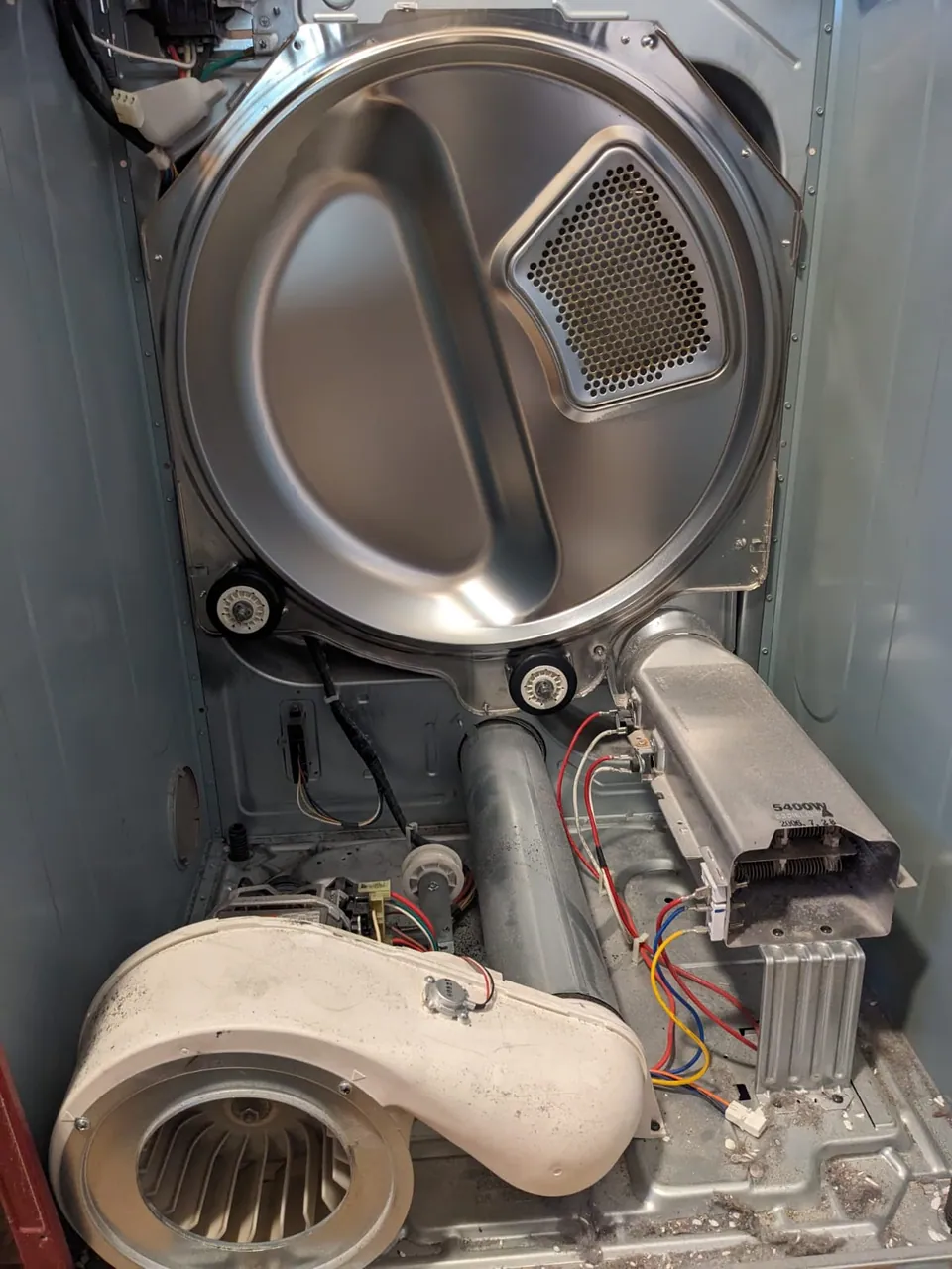 A dryer opened to access its drum, blower and internal components