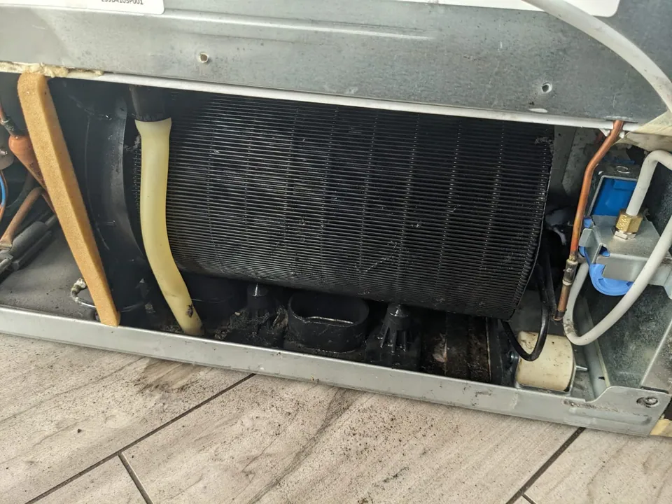 Accessible refrigerator condenser coils behind the lower service panel