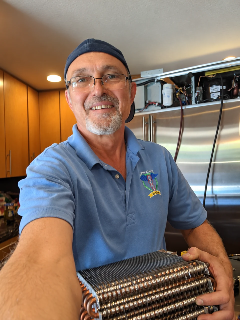 A Phoenix Appliance Services technician smiling during a refrigerator service visit