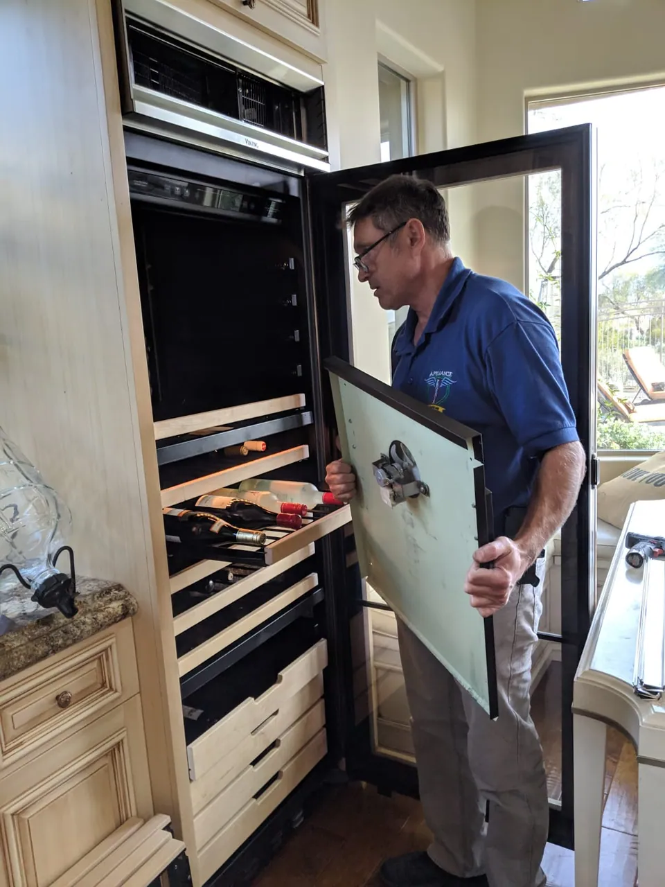 A technician working on a wall oven with its door removed