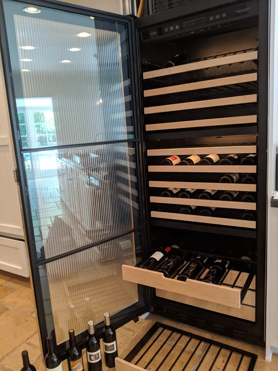 A built-in wine refrigerator with its door open and shelves visible
